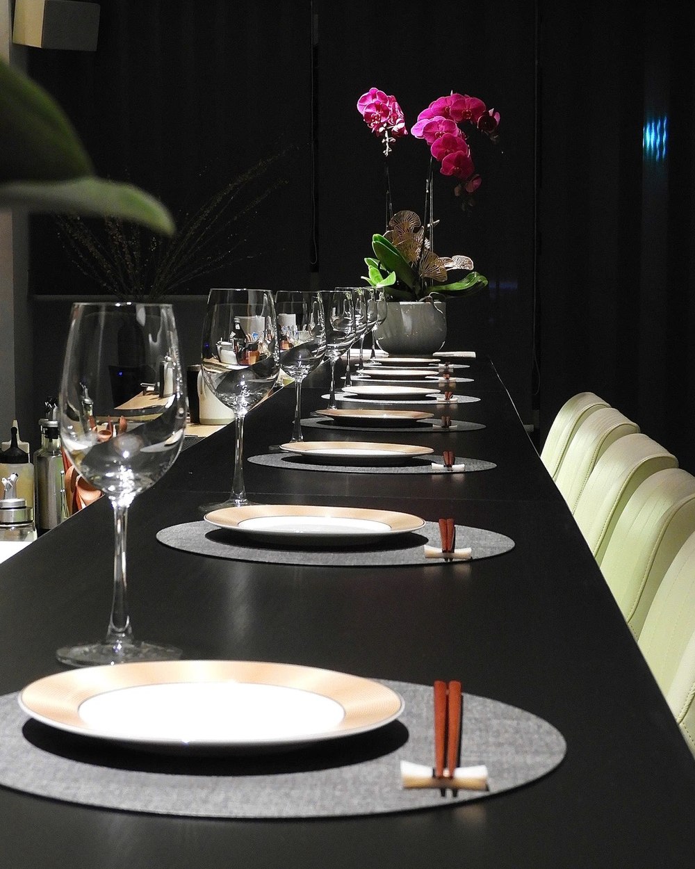 The full counter set and empty, awaiting one party, with an orchid centrepiece and low bar lighting.