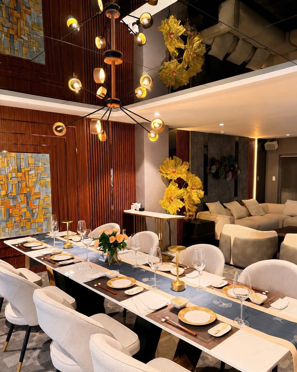 Kasen's private room, a long table set beneath a sculptural chandelier, with two abstract paintings and a lounge area visible behind.